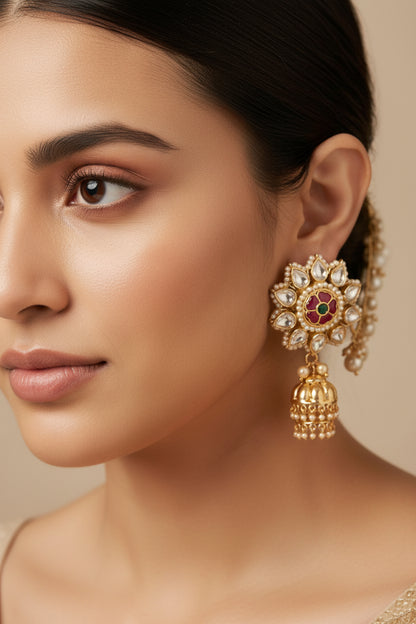 Ornate gold earring with pearls and gemstones worn by a person